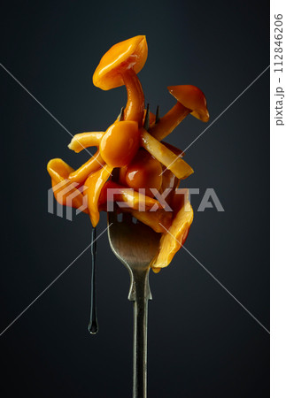 Pickled honey mushrooms on a fork. Pickled honey mushrooms on a fork. 112846206