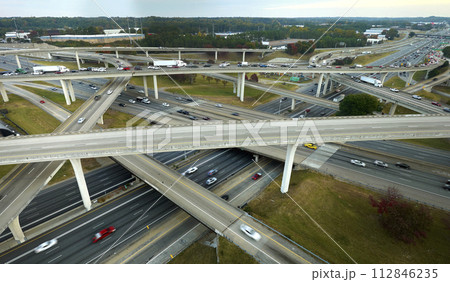 American freeway intersection with fast driving cars and trucks. View from above of USA transportation infrastructure American freeway intersection with fast driving cars and trucks. View from above of USA transportation infrastructure 112846235