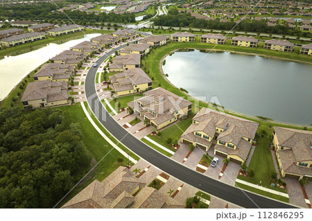 Aerial view of tightly packed homes in Florida closed living clubs with lake water in the middle. Family houses as example of real estate development in american suburbs 112846295