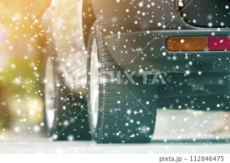 Close up detail car wheel with new black rubber tire protector on winter snow covered road. Transportation and safety concept. Close up detail car wheel with new black rubber tire protector on winter snow covered road. Transportation and safety concept. 112846475