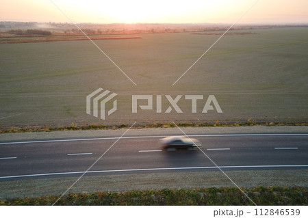 Aerial view of intercity road with blurred fast driving car at sunset. Top view from drone of highway traffic in evening 112846539