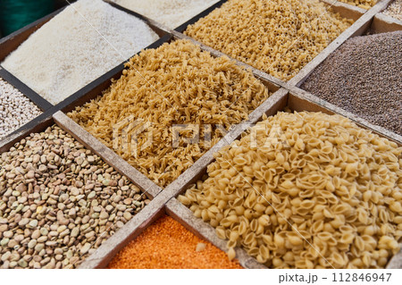 Variety organic groats in box on sale on a farmers market, ecological cereal products,pasta, fava beans, lentils. Food background 112846947