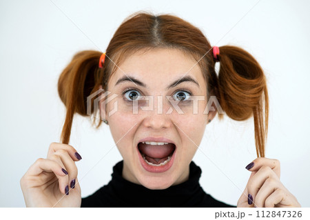 Closeup portrait of a funny redhead teenage girl with childish hairstyle smiling happily isolated on white backround. Closeup portrait of a funny redhead teenage girl with childish hairstyle smiling happily isolated on white backround. 112847326