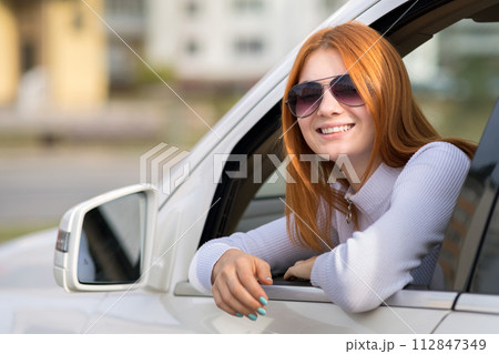 Young woman with red hair driving a car. Young woman with red hair driving a car. 112847349