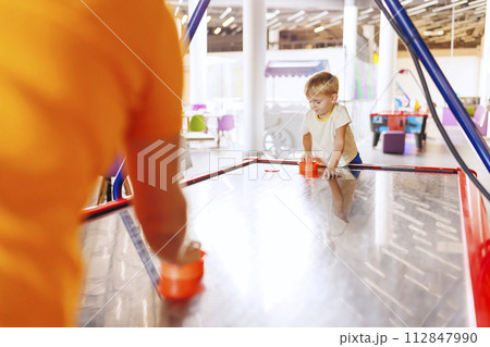 Boy playing air hockey in indoor play area. Boy playing air hockey in indoor play area. 112847990