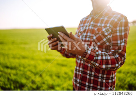 Tablet in the hands of a farmer. Smart farm. Farmer checking his crops on an agricultural field. Tablet in the hands of a farmer. Smart farm. Farmer checking his crops on an agricultural field. 112848266