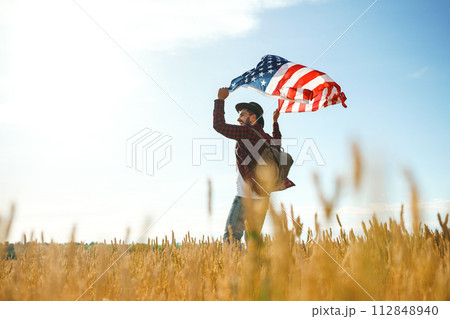 4th of July. American Flag.Patriotic holiday. Traveler with the flag of America. Beautiful sunset light. American style. 4th of July. American Flag.Patriotic holiday. Traveler with the flag of America. Beautiful sunset light. American style. 112848940