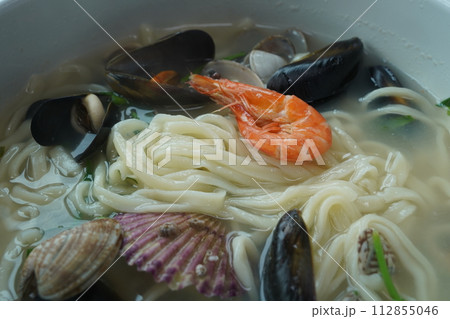 Kalguksu with seafood is made by boiling thin noodles with seafood, such as shrimp, octopus, and clam, in a baby clam broth. Kalguksu with seafood is made by boiling thin noodles with seafood, such as shrimp, octopus, and clam, in a baby clam broth. 112855046