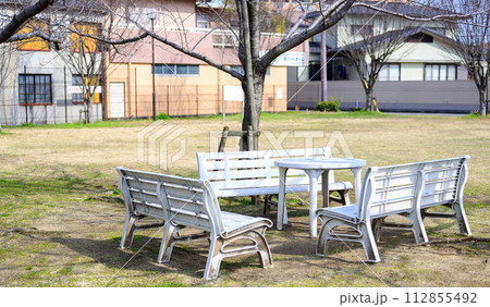 公園の春の一角に置かれた白いガーデン家具 公園の春の一角に置かれた白いガーデン家具 112855492