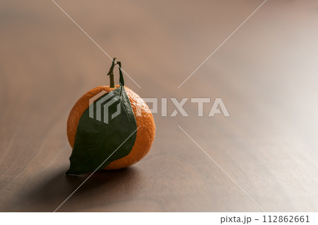 Small organic tangerine with leaves on wood table 112862661