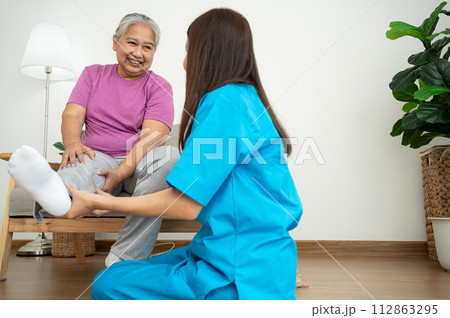 A young Asian women Physiotherapist Nursing is assisting an elderly woman exercise stretching muscles at home or a premium clinic for recovery, concept of Physical Therapy. 112863295