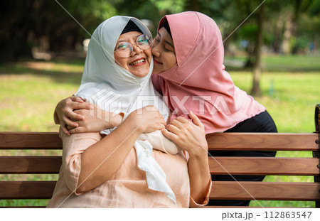 Muslim careful caregiver or nurse taking care of the patient in the hospital park. Happy Muslim mother in hijab hugging daughter. Concept of Savings and Senior Health Insurance, a Happy Family Muslim careful caregiver or nurse taking care of the patient in the hospital park. Happy Muslim mother in hijab hugging daughter. Concept of Savings and Senior Health Insurance, a Happy Family 112863547
