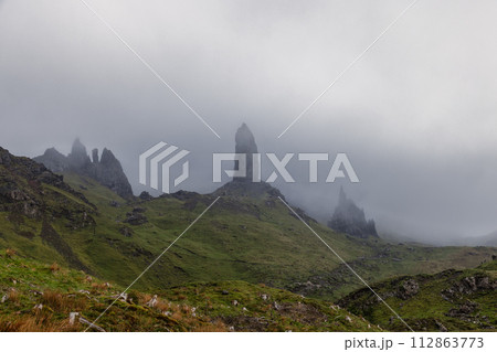 Distinctive pinnacle, the Old Man of Storr, pierces the fog on the Isle of Skye rugged landscape 112863773