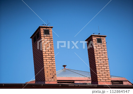 A tall chimney clinker brick built on the roof of a public building. 112864547