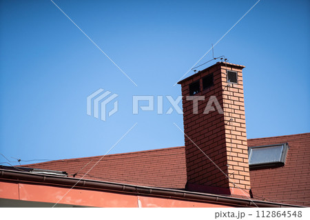 A tall chimney clinker brick built on the roof of a public building. A tall chimney clinker brick built on the roof of a public building. 112864548