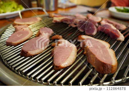 Duck meat is being grilled on the grill. 112864878