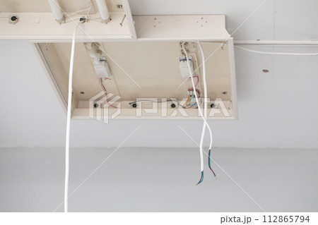 The lamp mounted on the ceiling is waiting to be connected by an electrician. 112865794