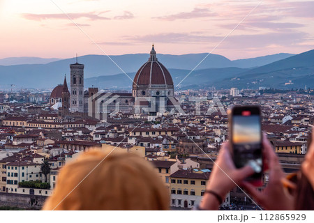Large tourist crowd on Piazzale Michelangelo enjoying sunset over Florence 112865929