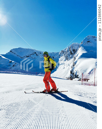 Skier in a bright outfit overlooking a snowy mountain Skier in a bright outfit overlooking a snowy mountain 112866042