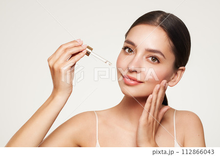 Young beautiful woman applying face serum 112866043