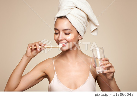 Young happy positive woman brushing her teeth Young happy positive woman brushing her teeth 112866048