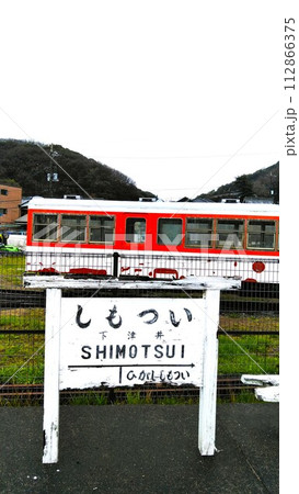 倉敷市児島で下津井電鉄の廃線跡、風の道に保存されてる旧下津井駅と旧車両とホームに立つしもついの看板 112866375