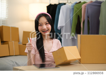 Startup small business owner working at home, woman writing address on parcel box at home for delivery order to customer, Online shopping business, ecommerce concept 112866938