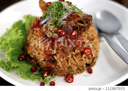 Thai food, Fried jasmine rice with canned fish mackerel in tomato sauce, topped with red chili, red onion, lettuce and kaffir lime leaves. 112867033