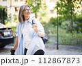 A woman is walking down a street, clutching a cup of coffee in her hand. 112867873