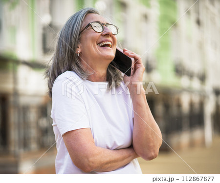 A woman wearing glasses is talking on her cell phone. 112867877