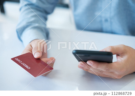A man is using his phone to pay for something with a credit card 112868729