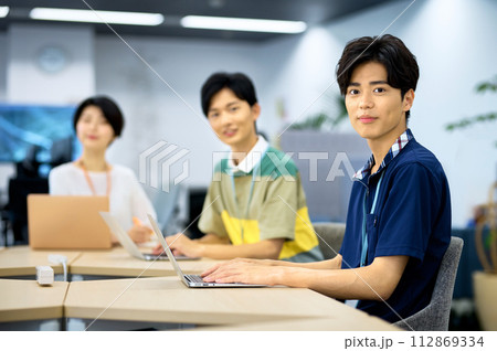 オフィスでデスクワークする若いITエンジニア オフィスでデスクワークする若いITエンジニア 112869334