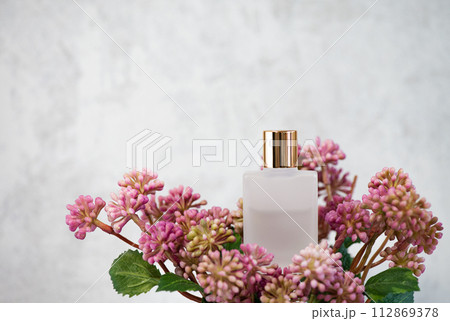 ピンク色の造花とゴールドの蓋のすりガラス製コスメボトル 112869378