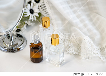 鏡と白い花と3種類のガラス製化粧品ボトル 112869383
