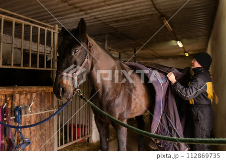 Tacking up a black horse in stable Tacking up a black horse in stable 112869735