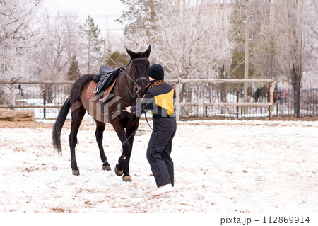 Person leading a lively horse in snow. Dressage. Person leading a lively horse in snow. Dressage. 112869914