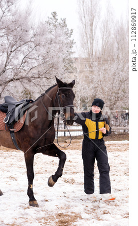 Person leading a lively horse in snow. Dressage. Person leading a lively horse in snow. Dressage. 112869917
