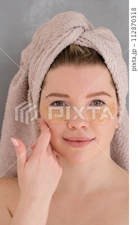 Applying eye patches in skincare routine. 112870318