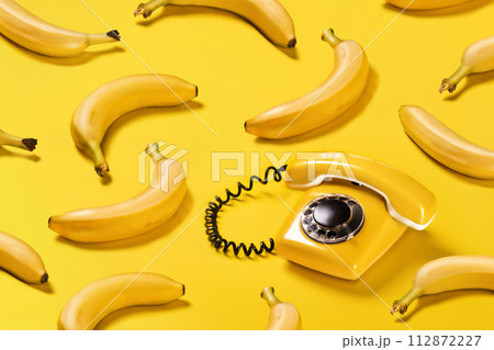 Creative pattern bananas and old yellow phone with hard shadows pattern on yellow background flat lay bananaphone Creative pattern bananas and old yellow phone with hard shadows pattern on yellow background flat lay bananaphone 112872227