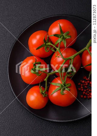 Fresh red cherry tomatoes on a branch on a dark concrete background 112873073