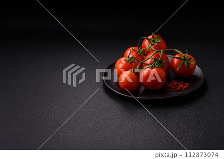 Fresh red cherry tomatoes on a branch on a dark concrete background 112873074