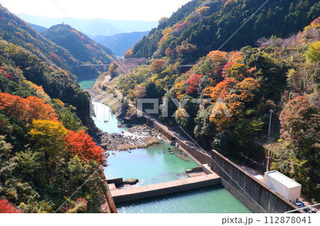 二川ダムの堰堤から眺めた、有田川と紅葉の山並み 112878041