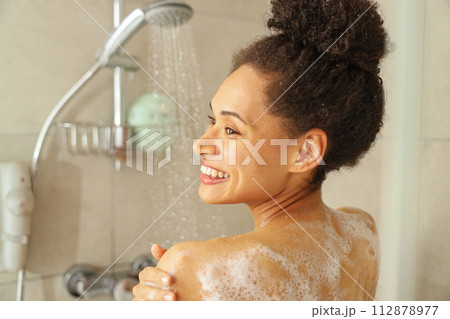 Chin raised, eyebrows raised, jaw relaxed, happy smile as she showers 112878977