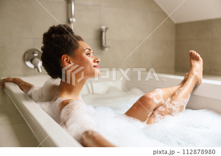 Human body immersed in water, enjoying a bath filled with foam for comfort 112878980