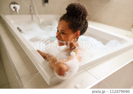 Woman enjoying a relaxing bath in a foamfilled bathtub, smiling and having fun 112879090