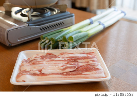 しゃぶしゃぶセットがテーブルに置かれている カセットコンロと白ネギと豚肉のスライス しゃぶしゃぶセットがテーブルに置かれている カセットコンロと白ネギと豚肉のスライス 112885558