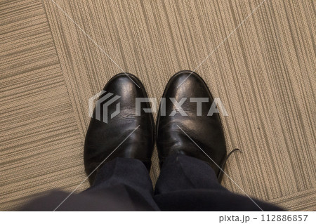 A man in elegant black shoes indoors. 112886857