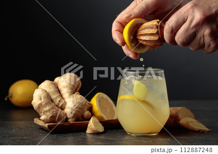 Ginger Ale with ice and lemon on a black background. 112887248
