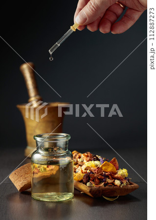 Dropping essential oil or herbal tincture into a small bottle. Dropping essential oil or herbal tincture into a small bottle. 112887273