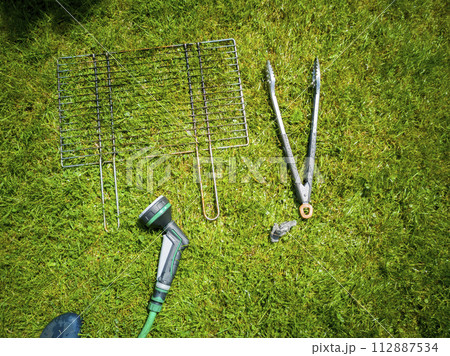 BBQ grillage rost lying on the wet lawn 112887534